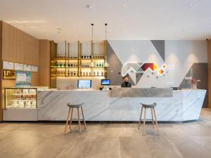 une femme debout à un comptoir dans un magasin dans l'établissement Borrman Hotel Jining Rencheng District Government Zhongde Plaza, à Liuxing