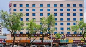 un grand bâtiment blanc avec des arbres devant lui dans l'établissement Borrman Hotel Huizhou West Lake Shuidong Street, à Huizhou