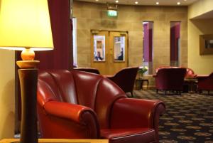 a living room filled with furniture and a red chair at Leapark Hotel in Grangemouth