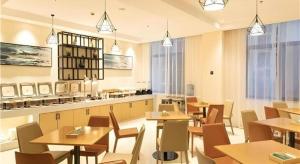 ein Restaurant mit Holztischen und -stühlen und Fenstern in der Unterkunft City Comfort Inn Tonglu Fuchun River Qiaolin Road in Tonglu