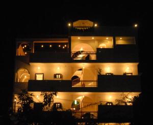 Un grand bâtiment blanc avec des lumières allumées la nuit dans l'établissement Dia Homestay, à Pushkar