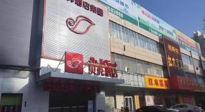 un bâtiment avec des panneaux sur le côté dans l'établissement Shell Hotel Liaocheng Dongchang Xi Road Railway Station, à Liaocheng