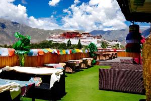 d'une terrasse avec des tables et des chaises et des montagnes en arrière-plan. dans l'établissement City Comfort Inn Lhasa Potala Palace Scenic View, à Lhasa