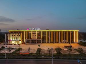 ein großes Gebäude mit einem Parkplatz davor in der Unterkunft Echarm Hotel Fangchenggang Qisha in Gongche