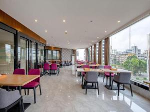 ein Restaurant mit Tischen und Stühlen und großen Fenstern in der Unterkunft Borrman Hotel Fangchenggang Cross-sea Bridge in Gongche