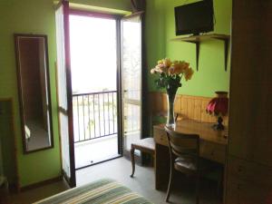 una habitación con escritorio y un jarrón de flores sobre una mesa en Hotel La Capannina, en Massino Visconti