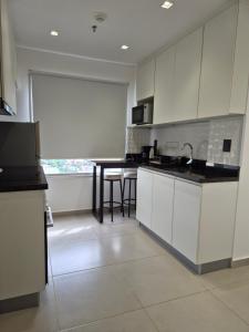 a kitchen with white cabinets and a table at Molas Tower 119D in Asunción