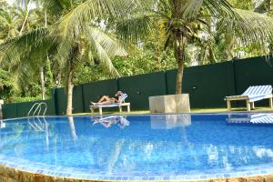 una mujer sentada en una silla junto a una piscina en Jonathan`s way, en Negombo