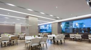 une salle à manger avec tables et chaises dans un bâtiment dans l'établissement Borrman Hotel Golden Crown Liuzhou Wuxing Pedestrian Street, à Liuzhou