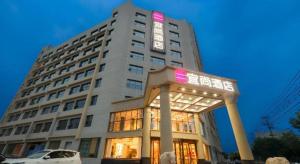 un grand bâtiment blanc avec une enseigne dessus dans l'établissement Echarm Hotel Hengshui 2nd High School High-speed Railway Station, à Hengshui