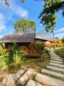 une maison avec un toit de chaume et un chemin dans l'établissement Phuree Hut, à Ko Phayam