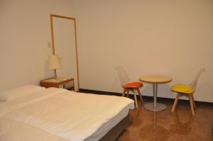 Un dormitorio con una cama y dos sillas y una mesa. en GOOSESTAY Koza, en Okinawa City