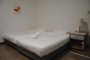 two white beds in a room with a night stand at GOOSESTAY Koza in Okinawa City