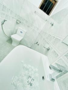 Un baño blanco con inodoro y ducha. en Hikka Heaven Guest House, en Hikkaduwa