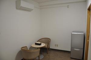 Una habitación con dos sillas y una mesa y un refrigerador. en GOOSESTAY Koza, en Okinawa City