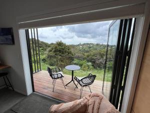 une chambre avec un balcon avec une table et des chaises dans l'établissement Hidden Valley Waiheke, à Palm Beach
