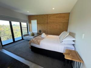 une chambre avec un grand lit blanc et un canapé dans l'établissement Hidden Valley Waiheke, à Palm Beach
