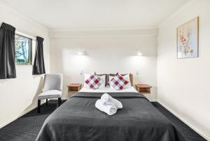 a bedroom with a bed and a chair at New Castle Motor Lodge in Rotorua