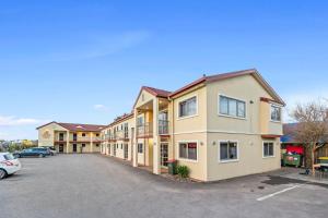 a large apartment building with a car parked in a parking lot at New Castle Motor Lodge in Rotorua