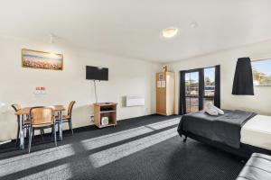 a hotel room with a bed and a table and chairs at New Castle Motor Lodge in Rotorua +20 photos