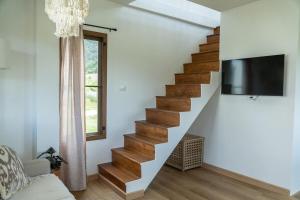 een woonkamer met een houten trap en een tv bij Baan Lek Pai in Pai