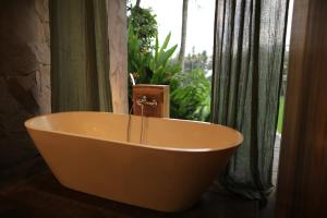 una bañera en un baño con ventana en Soma Beach House, en Balian