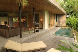 Un patio con piscina y una casa. en Soma Beach House, en Balian