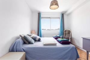 ein Schlafzimmer mit einem Bett mit einer blauen Decke und einem Fenster in der Unterkunft Le Clos Des Violettes in Toulouse