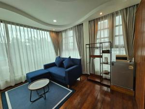 a living room with a blue couch and a table at Madugu Service Apartment in Chiang Mai