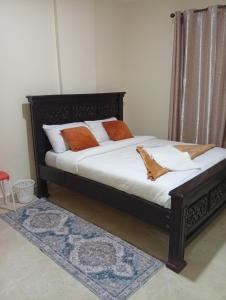 a bed with orange and white pillows in a room at JO kitengela deluxe Two and one bedroom in Kitengela 