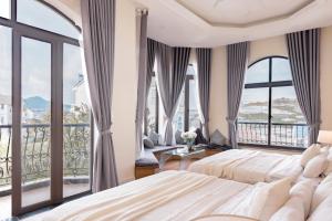 a bedroom with two beds and a balcony at An Nhiên Hotel & Villa Da Lat in Da Lat