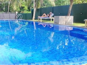 una mujer sentada en una silla junto a una piscina en Jonathan`s way, en Negombo