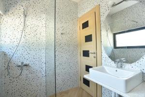 um banheiro com uma pia, um chuveiro e um espelho em Lux Čanj em Čanj mais 35 fotografias