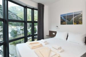 um quarto com uma cama branca e uma grande janela em Lux Čanj em Čanj