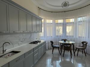 a kitchen with white cabinets and a table with chairs at B&B Apartment Farhad Hospitality Solutions in Samarkand