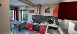 a kitchen with red cabinets and a table with chairs at Appartement entre Sisteron et Gorges de la Méouge " Les Hauts de Toscane " in Ribiers