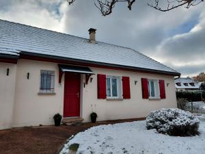 a white house with red doors and snow on the ground at Spacieuse maison "Des 3 filles" pour 6 personnes in Ally