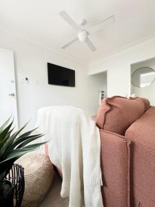 Brisbane CBD - 2BR - Sleeps 6 - Snacks WIFI - Parking في بريزبين: غرفة معيشة مع أريكة ومروحة سقف
