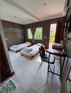 a bedroom with two beds and a desk and a chair at We Home Guesthouse in Ban Pa Bong