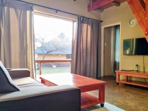 a living room with a couch and a table and a large window at Vakasha Lodge in Siphofaneni