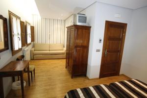 Habitación con cama, mesa y TV en un armario. en Hostal Rey Pedro I en Santo Domingo de la Calzada