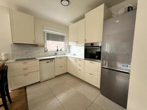 a kitchen with white cabinets and a stainless steel refrigerator at Cozy&Spacious apartment with garden in Antwerp