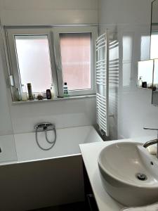 a white bathroom with a sink and two windows at Cozy&Spacious apartment with garden in Antwerp