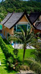 a house with a palm tree in front of it at Juga Beach Front Villa 3B Koh Chang in Ko Chang +8 photos