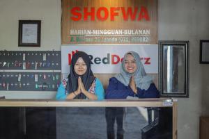 two women standing in front of a window at RedDoorz near Juanda International Airport 2 in Sidoarjo +40 photos
