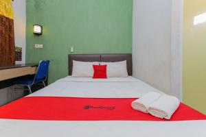 a bedroom with a bed with a red pillow and towels at RedDoorz near Juanda International Airport 2 in Sidoarjo