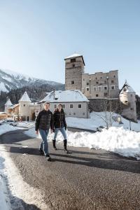Zwei Menschen laufen eine Straße im Schnee entlang in der Unterkunft Apart Sonnenblick in Landeck