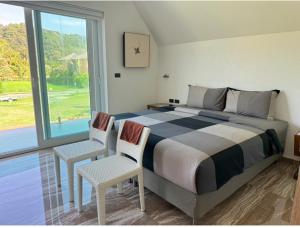 a bedroom with a bed and two chairs and a window at Juga Beach Front Villa 3B Koh Chang in Ko Chang