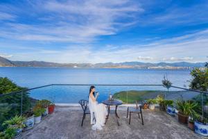 a woman standing on a balcony with a view of the water at Blue Sea Hotel in Dali