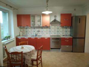 eine Küche mit roten Schränken und einem Tisch mit Stühlen in der Unterkunft U bram Podbeskidzia in Ligota